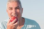 man with dentures biting apple