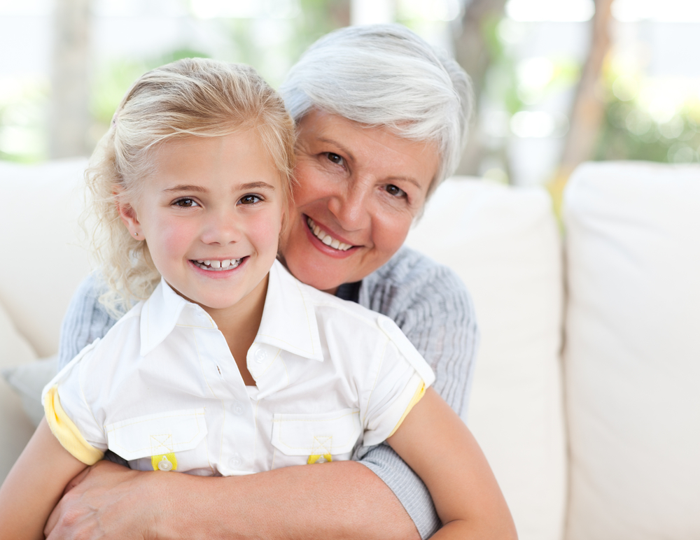 portrait of smiling grandmother and granddaughter in their home
